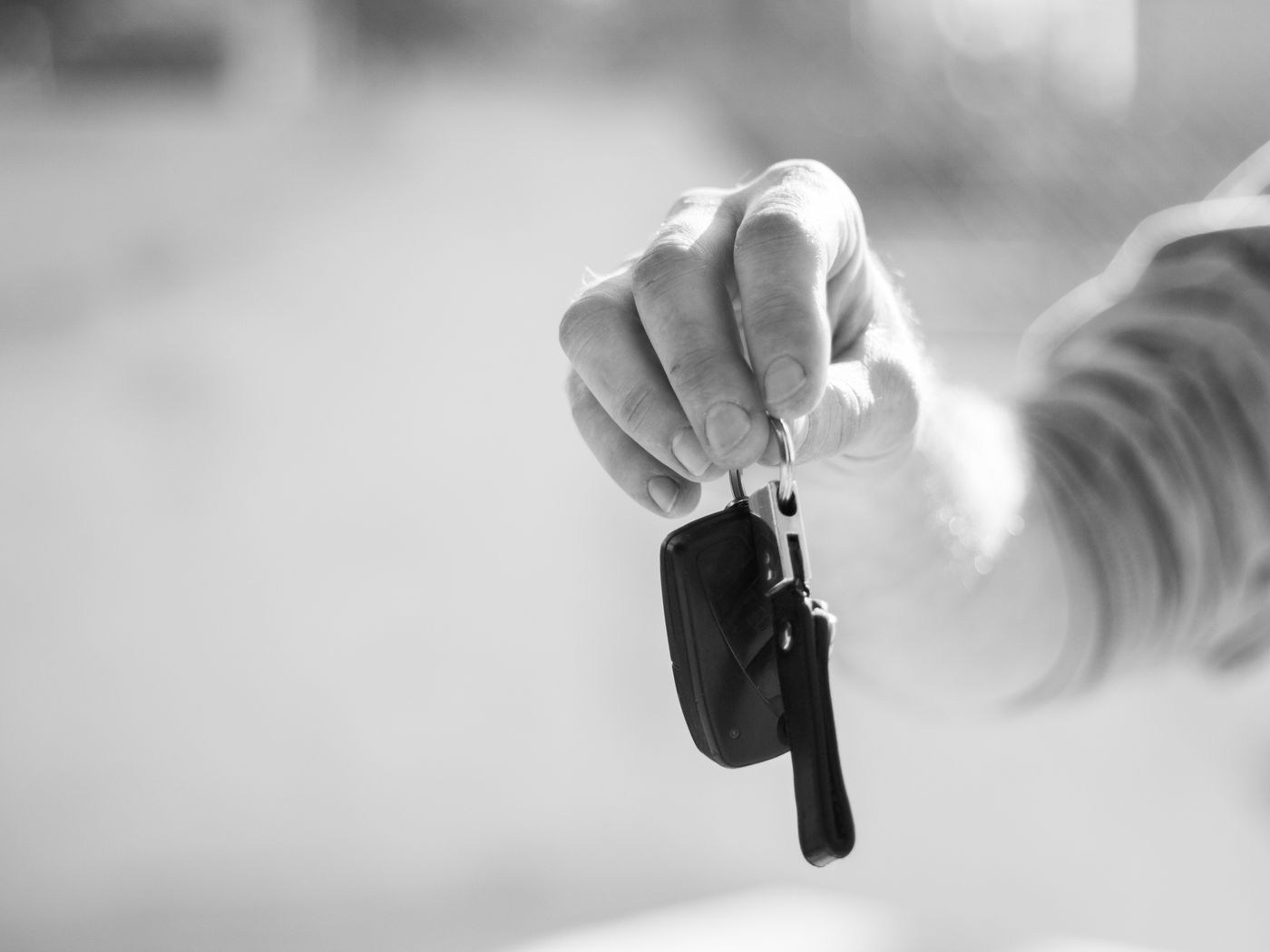 A hand holding out a set of car keys